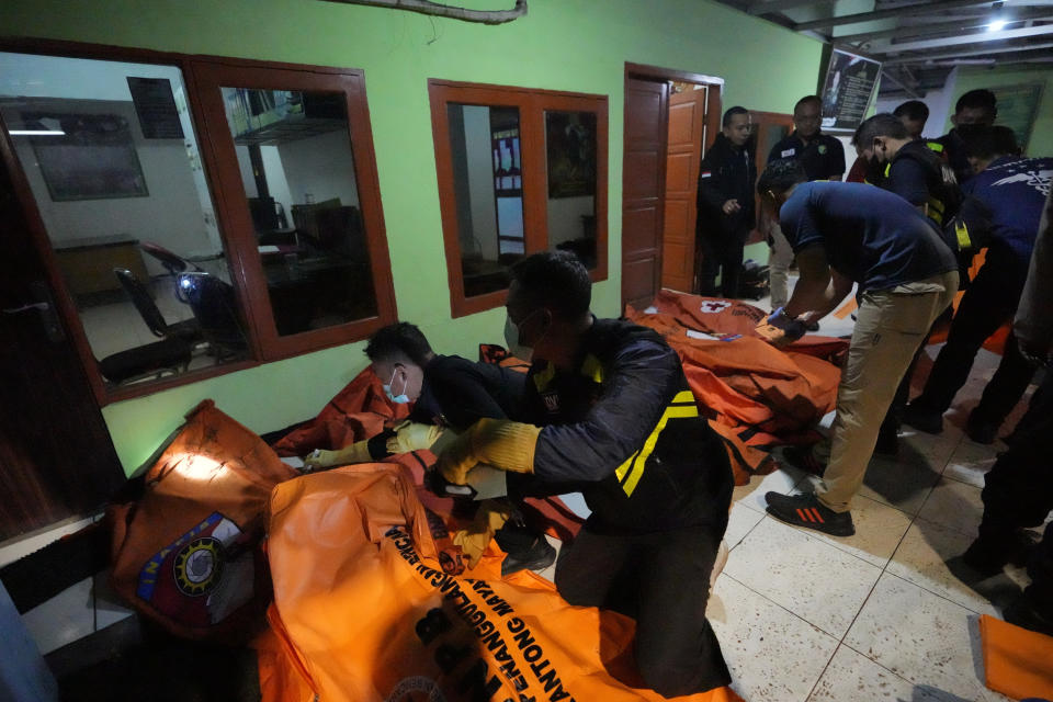 Indonesian police inspect body bags of victims after a fire broke out at a neighborhood in Jakarta, Indonesia, Friday, March 3, 2023. A large fire broke out at a fuel storage depot in Indonesia's capital on Friday, killing several people, injuring dozens of others and forcing the evacuation of thousands of nearby residents after spreading to their neighborhood, officials said. (AP Photo/Achmad Ibrahim)