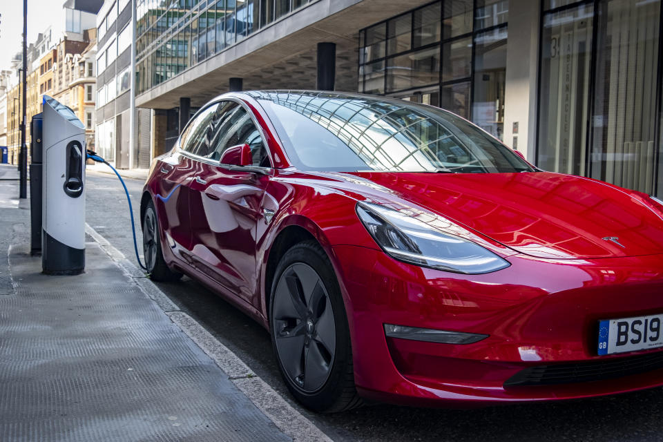 London, June 2020: A red Tesla Model 3 parks and charges in a designated charging bay in central London.