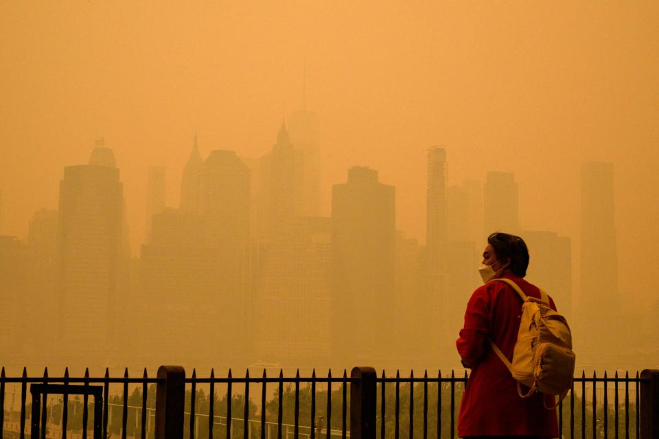 A person wears a face mask as smoke from wildfires in Canada cause hazy conditions in New York City on June 7, 2023. An orange-tinged smog caused by Canada's wildfires shrouded New York on Wednesday, obscuring its famous skyscrapers and causing residents to don face masks, as cities along the US East Coast issued air quality alerts. (Photo by ANGELA WEISS / AFP) (Photo by ANGELA WEISS/AFP via Getty Images)