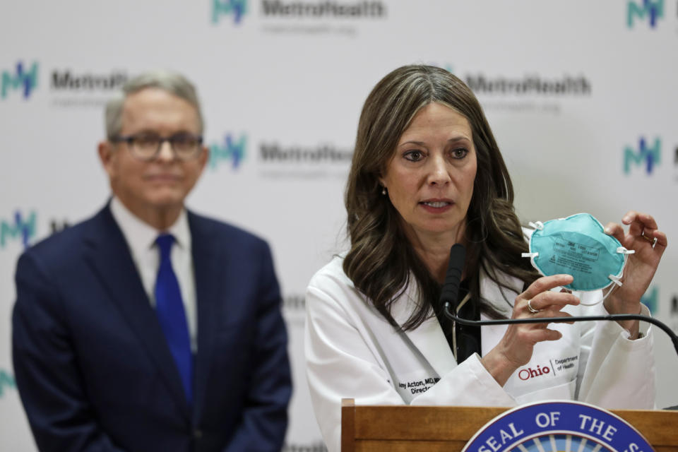 FILE - In this Feb. 27, 2020 file photo Ohio Department of Health Director Amy Acton speaks during a news conference at the MetroHealth Medical Center in Cleveland. Ohio Gov. Mike DeWine, left, watches. Under pressure from law enforcement, Tennessee's top health officials quietly agreed in April to release the names and addresses of those who had been treated or exposed to COVID-19 to police departments and sheriff's offices. Acton issued an order April 24 requiring local health departments to provide emergency dispatchers the names and addresses of people within their jurisdictions who tested positive. The order required dispatchers to treat the data as “protected health information” and to remove it from the system once a person has recovered from the illness, although the order is unclear on how dispatching agencies would learn of this follow-up information. (AP Photo/Tony Dejak, file)