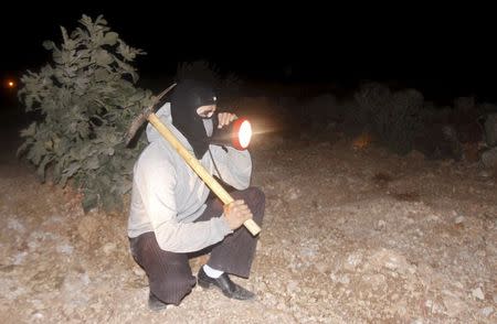 A masked Palestinian villager keeps guard with other Palestinians as they tighten night patrols against Jewish settler threats, at Qusra village near the West Bank city of Nablus August 10, 2015. REUTERS/Abed Omar Qusini