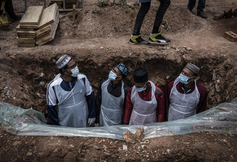 Members of the Saaberie Chishty Burial Society prepare the grave for the burial of a person who died from COVID-19 at the Avalon Cemetery in Lenasia, Johannesburg Saturday Dec. 26, 2020. South Africa’s health minister has announced an “alarming rate of spread” in the country, with more than 14,000 new confirmed coronavirus cases and more than 400 deaths reported Wednesday. It was the largest single-day increase in cases. (AP Photo/Shiraaz Mohamed)