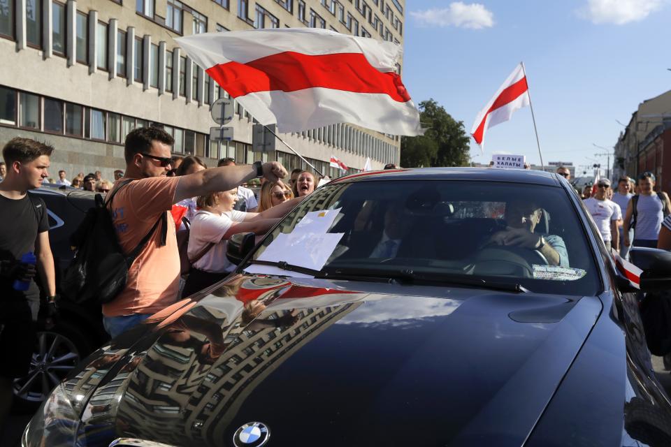 People block a car carrying Uladzimir Karanik, Minister of Health of the Republic of Belarus, is seen on the left inside a car, during a rally in Minsk, Belarus, Monday, Aug. 17, 2020. Workers heckled and jeered President Alexander Lukashenko on Monday as he visited a factory and strikes grew across Belarus, raising the pressure on the authoritarian leader to step down after 26 years in power. (AP Photo/Sergei Grits)