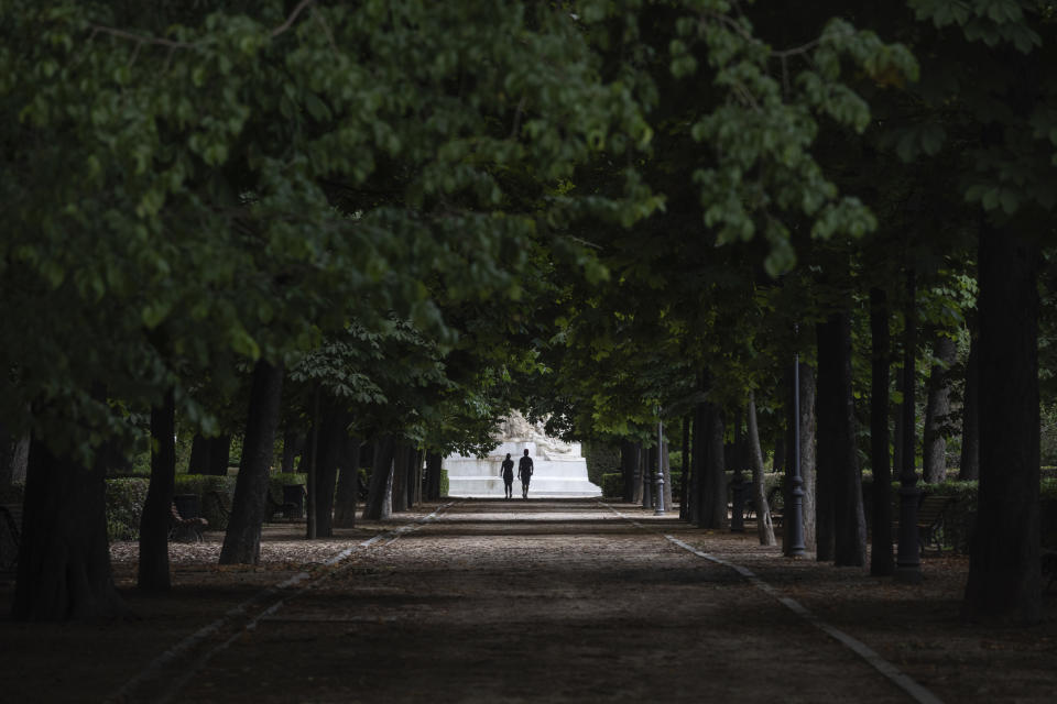 A couple walk through the Retiro park in Madrid, Spain, Monday, May 25, 2020. Roughly half of the population, including residents in the biggest cities of Madrid and Barcelona, are entering phase 1 on Monday, which allows social gatherings in limited numbers, restaurant and bar service with outdoor sitting and some cultural and sports activities. (AP Photo/Bernat Armangue)