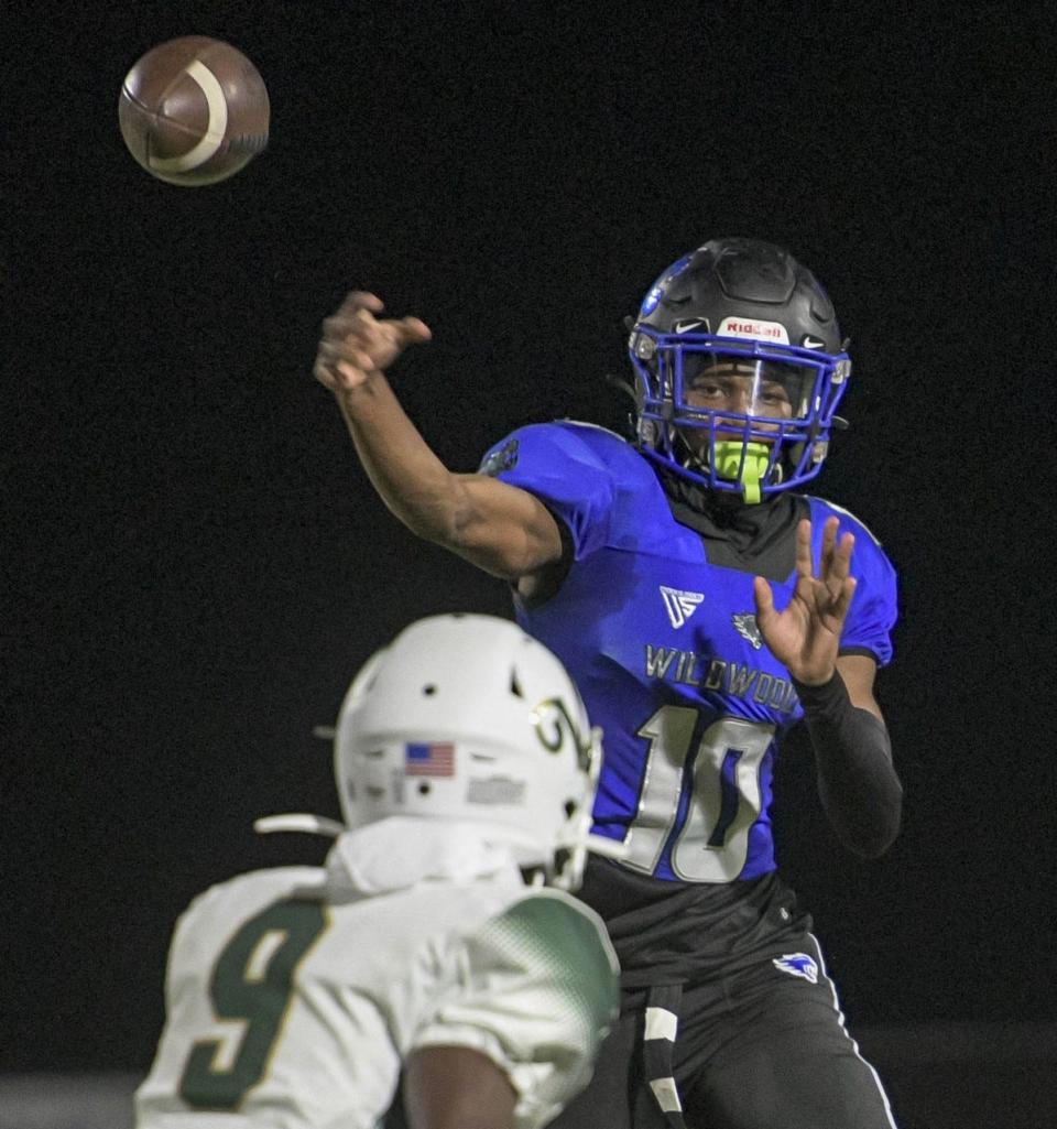 Wildwood's Jamari Dickens (10) passes under pressure from The Villages' DeShawn Bellamy (9) during a game between Wildwood High School and The Villages Charter High School in Wildwood on Friday, Oct. 21, 2022.