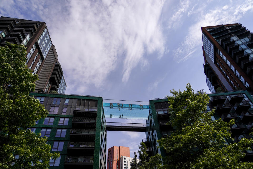 People swim in the elevated pool, called Sky Pool, in London, Monday, July 18, 2022. Britain's first-ever extreme heat warning is in effect for large parts of England as hot, dry weather that has scorched mainland Europe for the past week moves north, disrupting travel, health care and schools. (AP Photo/Alberto Pezzali)