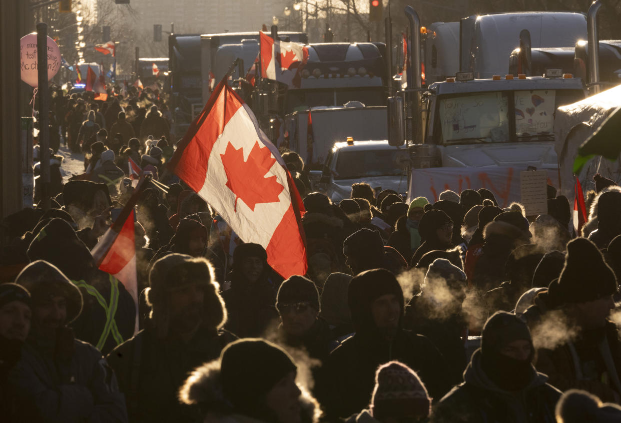Protesters walk around trucks parked in the downtown area in protest of COVID-19 restrictions, in Ottawa, Ontario, Saturday, Feb. 5, 2022. (Adrian Wyld/The Canadian Press via AP)