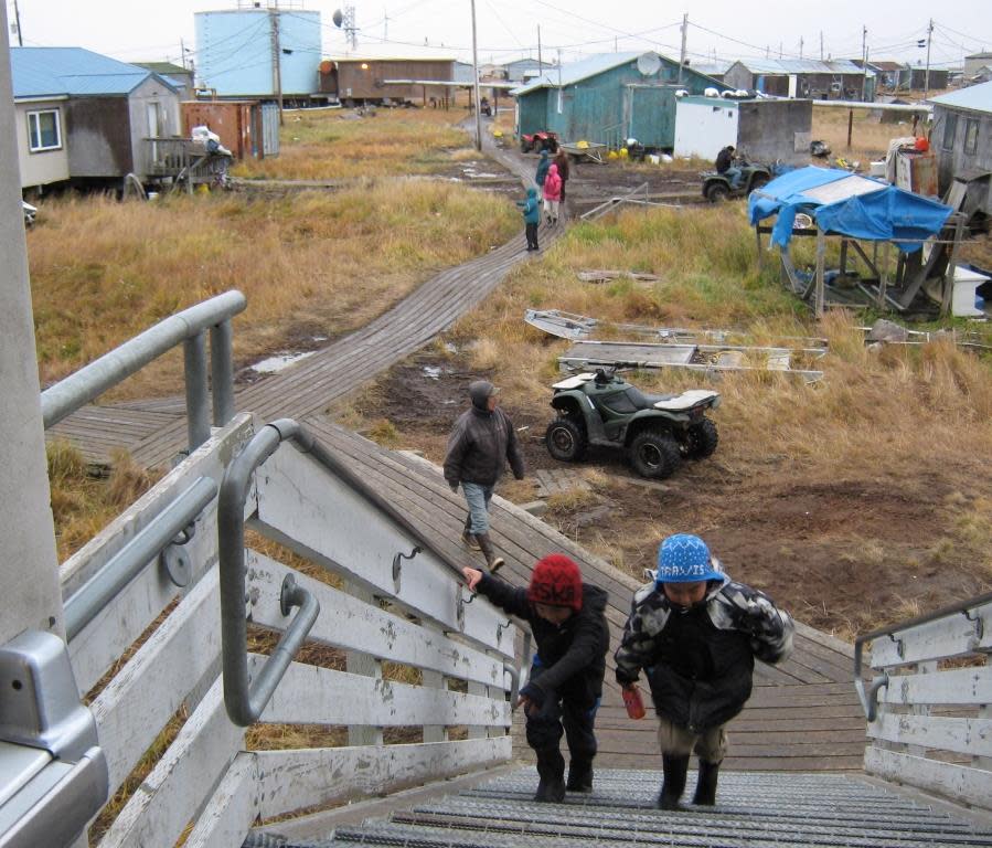 Children walk to school on a boardwalk in the village of Newtok in 2012. Residents have been moving in phases from the old site, which is undermined by erosion, flooding and permafrost thaw, to a new and safer village site called Mertarvik. (Photo provided by the Alaska Division of Community and Regional Affairs)