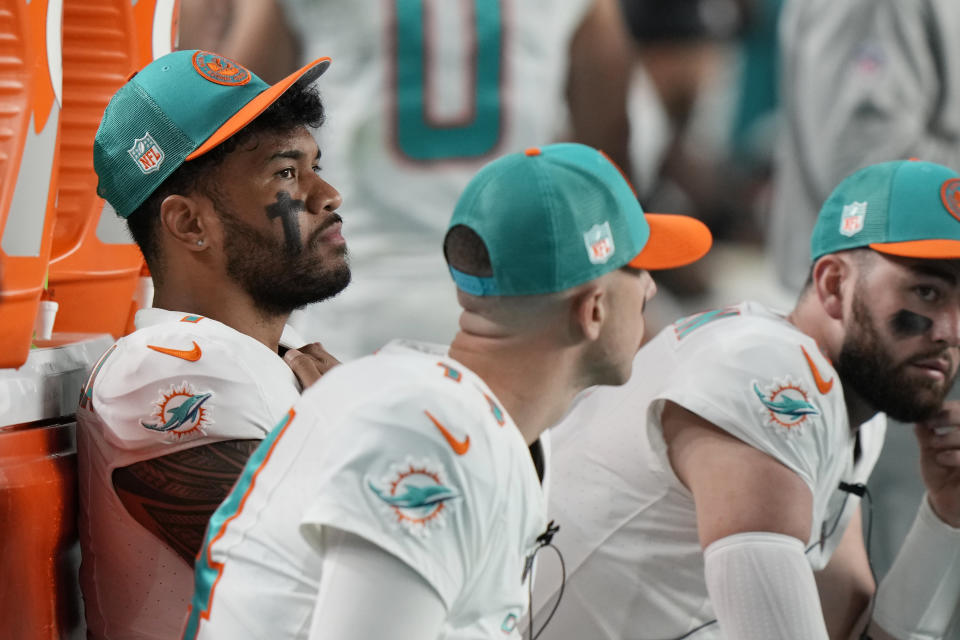 Miami Dolphins quarterback Tua Tagovailoa, left, sits on the sidelines during the second half of an NFL football game against the Buffalo Bills, Sunday, Jan. 7, 2024, in Miami Gardens, Fla. (AP Photo/Wilfredo Lee)