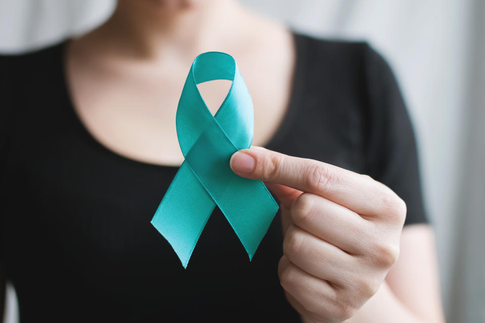 Woman holds in his hand Teal ribbon. Symbolic for cervical cancer, ovarian cancer, gynecological cancer and PCOS, sexual assault awareness. Women&#39;s health care. Banner