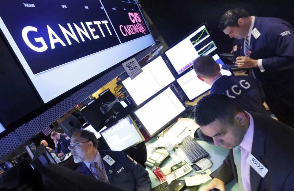 FILE - In this Aug. 5, 2014, file photo, specialist Michael Cacace, foreground right, works at the post that handles Gannett on the floor of the New York Stock Exchange. The Wall Street Journal is reporting that MNG Enterprises, better known as Digital First Media, is preparing to bid for newspaper publisher Gannett Co. (AP Photo/Richard Drew, File)