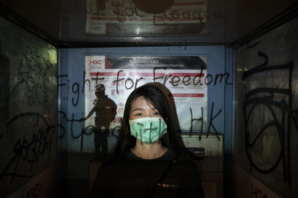 In this Oct. 19, 2019, photo, a 24-year-old protester who identified herself as Josephine, poses for a portrait as a projector displays a photograph, previously taken during the unrest, over her at a protest in Hong Kong. Josephine said she is afraid of the mask law, "but we are still coming out because we need to find hope, to find the future of Hong Kong." (AP Photo/Felipe Dana)