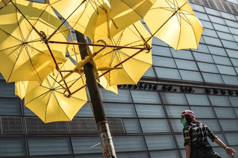 A pro-democracy protester stands under a display of yellow umbrellas after a barricade outside the CITIC Tower office block was removed, near a protest site in the Admiralty district of Hong Kong, on November 18, 2014