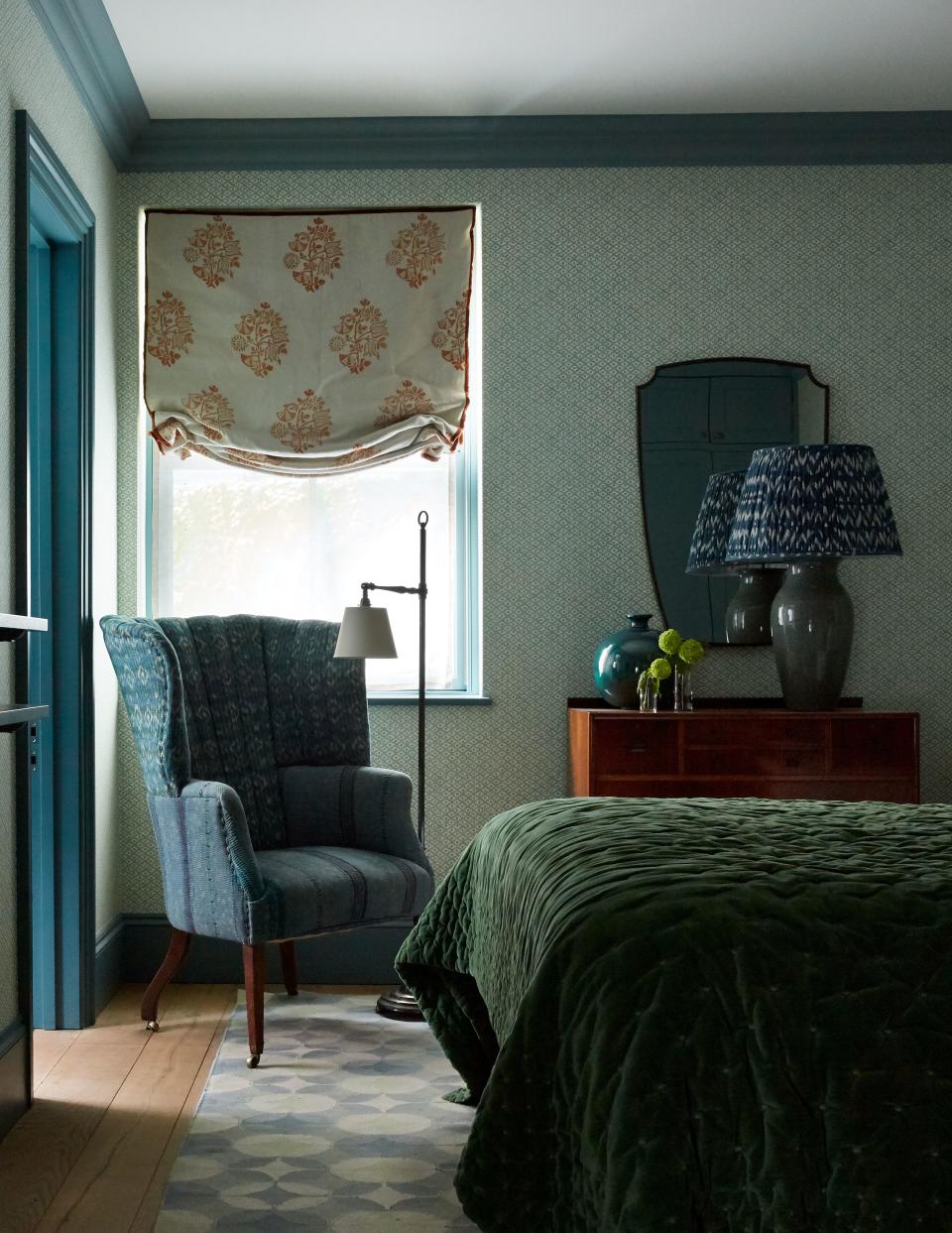 The tight color palette shows restraint in a guest bedroom that balances elegant prints, including the Galbraith & Paul wallpaper, an upholstered armchair from Dean Antiques, and a roman shade done in Tobias and the Angel linen.