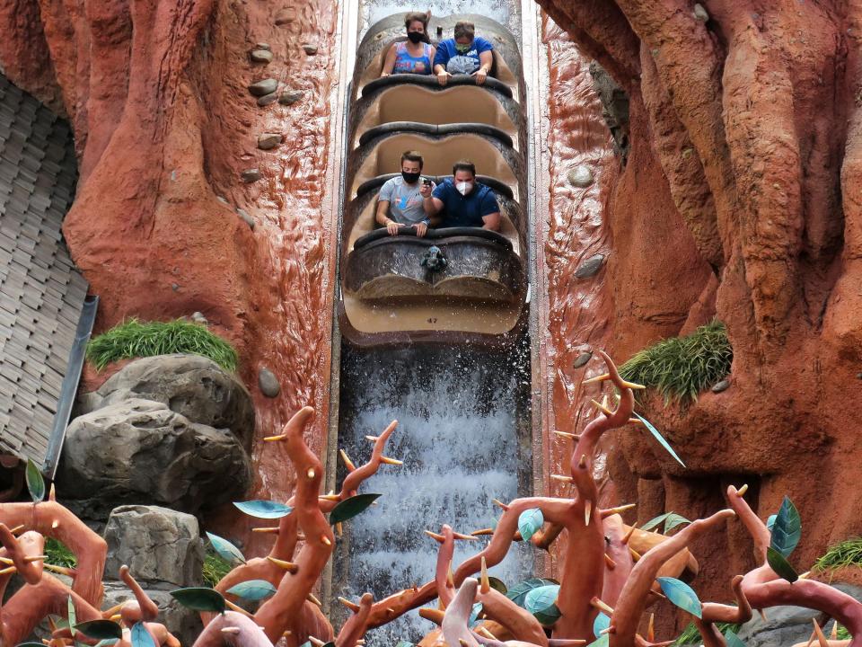 This image shows four people riding down a water attraction at Disneyland.