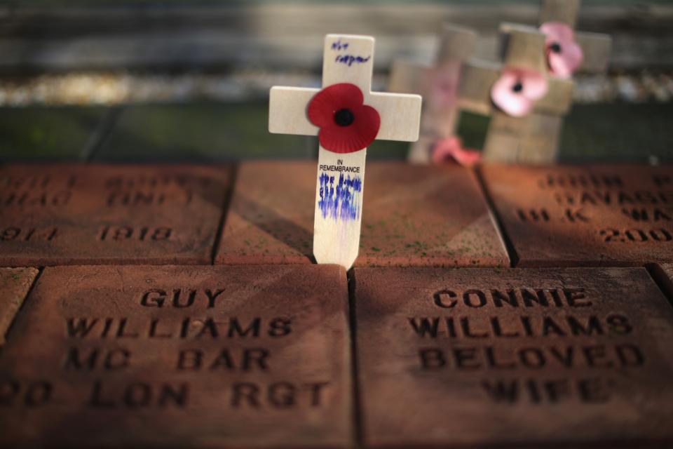 ALREWAS, UNITED KINGDOM - NOVEMBER 11: A cross and poppy are placed between memorial stones at The National Memorial Arboretum during the remembrance Service on November 11, 2012 in Alrewas, England. The Armed Forces Memorial, is the UK's tribute to the men and women who have been killed on duty or as a result of terrorist action since 1948. Their names are inscribed on the giant Portland stone walls. The obelisk is specifically dedicated to those who have died whilst in service. The Armed Forces Memorial has been designed to allow a shaft of sunlight to fall across the sculpted wreath on the central stone on Armistice Day at precisely 11:00am on the 11th day of the 11th month, the time when fighting formally stopped in World War I. (Photo by Christopher Furlong/Getty Images)