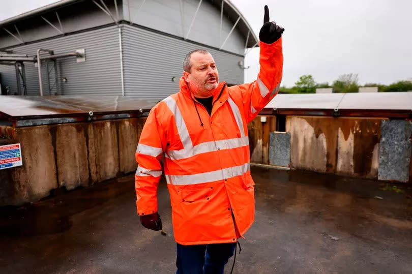 Gavin, stood on a platform at  the treatment works, points upwards while speaking