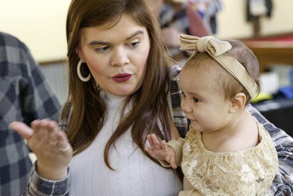 Morgan Shurtleff, left, shows her daughter, 1-year-old Cora Dibert, how to blow a kiss goodbye at The Bridge Church, Saturday, Dec. 2, 2023, in Mustang, Okla. After Cora's diagnosis of lead poisoning, Shurtleff was at work as a nurse, preparing to give a vaccination, when she noticed her young patient was eating a WanaBana apple cinnamon pouch. She immediately told the parent about the recall. (AP Photo/Nate Billings)