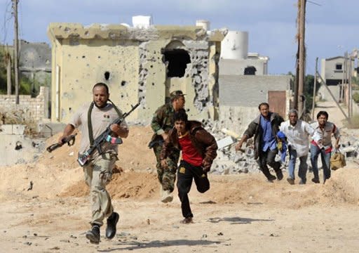 Libya's National Transitional Council (NTC) fighters escort civilians fleeing Sirte during heavy fighting. Libyan fighters raised the new government's flag over the oasis of Bani Walid Monday and hoped for the swift fall of the other remaining redoubt of Moamer Kadhafi loyalists, Sirte, as relatives of his henchmen fled