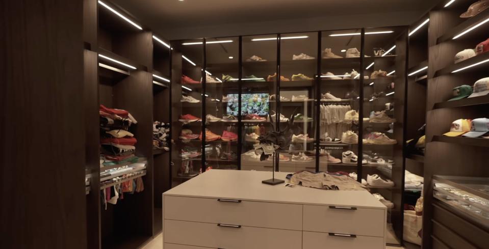 A walk-in closet with shelves of shoes.