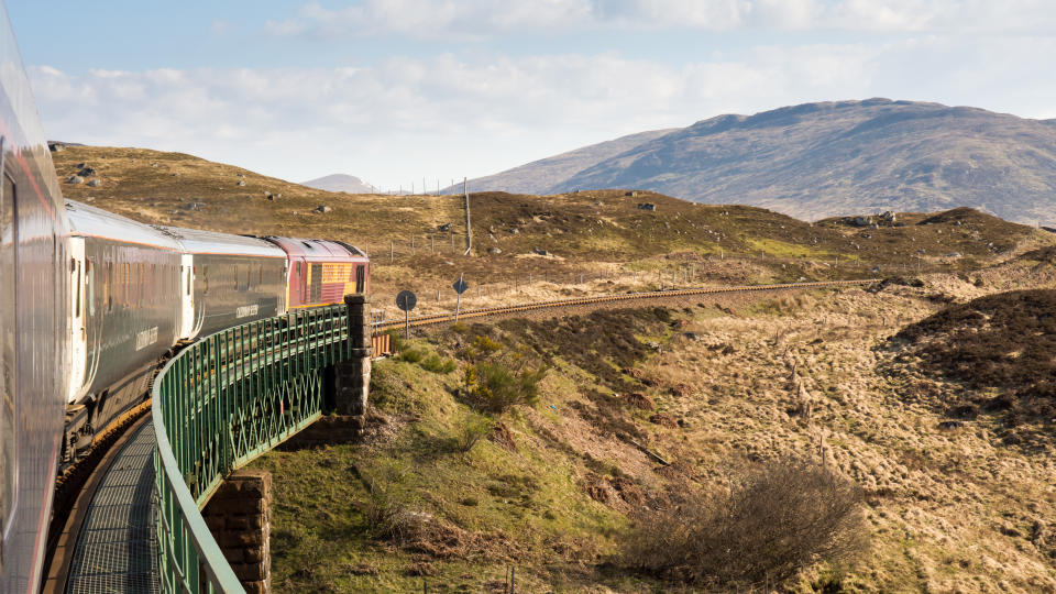 Rannoch, Scotland - May 11, 2016: Lit by the rising sun, the Caledonian Sleeper train crosses Rannoch Viaduct on the scenic West Highland Line railway in the Scottish Highlands.