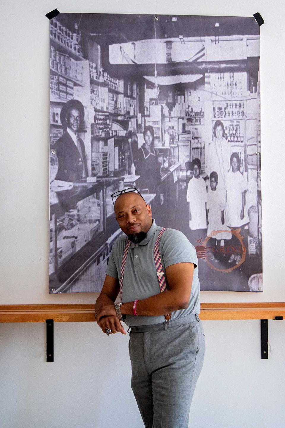 J. Hackett stands with an historic photograph of a black-owned Asheville business, one of several prominently displayed on the walls of Grind Coffee Co. in the River Arts District.