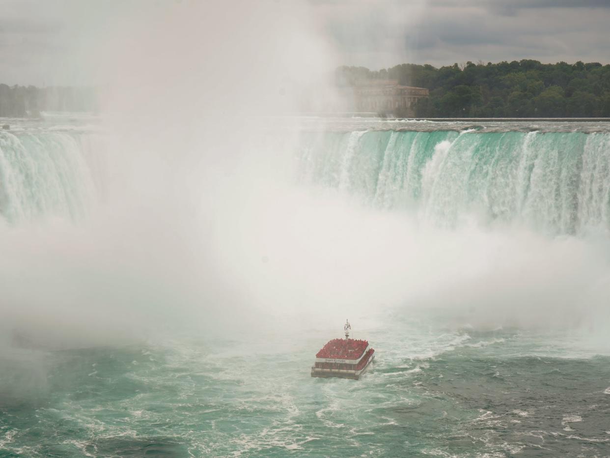 A boat approaches Horseshoe Falls at Niagara Falls on a cloudy day