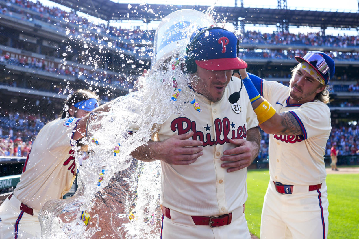 Philadelphia Phillies' J.T. Realmuto, center, is doused by Bryson Stott, right, and Brandon Marsh, left, after hitting a walkoff single off New York Mets' Edwin Díaz during the ninth inning of a baseball game, Sunday, Sept. 15, 2024, in Philadelphia. (AP Photo/Derik Hamilton)