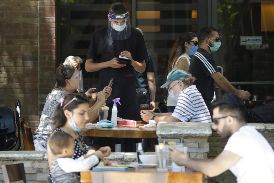 In this July 18, 2020 file photo, a waiter takes an order at a restaurant in Burbank, Calif.