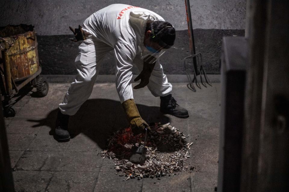 Este trabajador se afana en juntar toda la ceniza después de haber incinerado el cuerpo. (Photo by PEDRO PARDO/AFP via Getty Images)