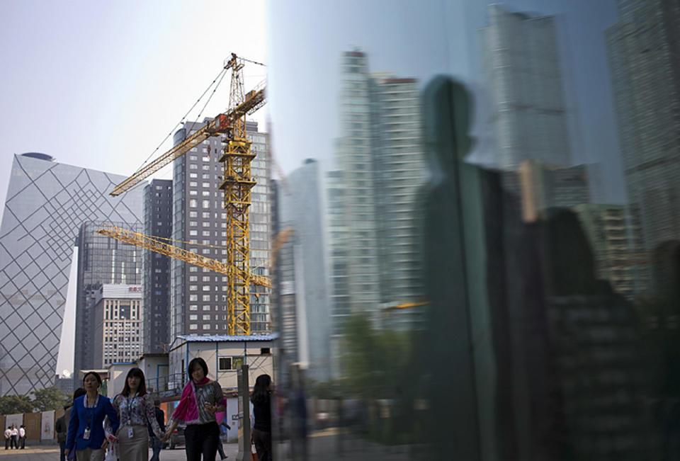 FILE - In this Oct. 8, 2013 file photo, Chinese people walk past a construction site and office buildings, which are reflected on window glass at the Central Business District in Beijing, China. Growth has marched steadily downward over the past two years as Beijing clamped down on a spending boom that analysts worry has pushed debt to dangerous levels. (AP Photo/Andy Wong, File)