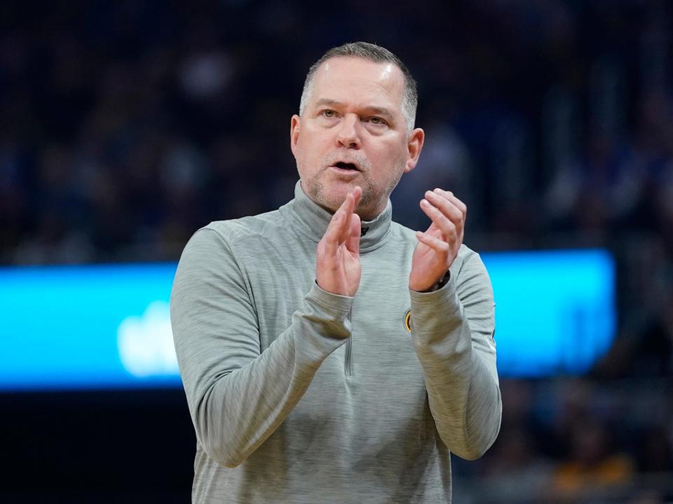 Michael Malone claps and looks up during a Nuggets game.