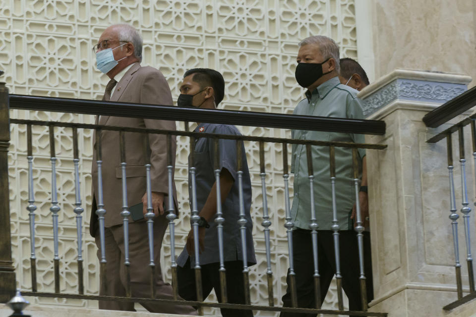 Former Malaysian Prime Minister Najib Razak, left, wearing a face mask arrives at Court of Appeal in Putrajaya, Malaysia, Monday, April 5, 2021. The court Monday began hearing an appeal by Najib to overturn his conviction and 12-year jail sentence linked to the massive looting of the 1MDB state investment fund that brought down his government in 2018. (AP Photo/Vincent Thian)