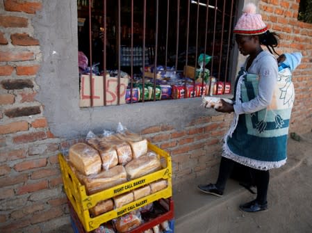 A woman buys bread at a shop in Chitungwiza, Zimbabwe