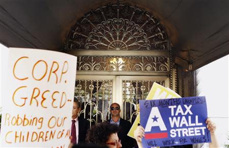 Members of the Occupy Wall St movement hold signs aloft while demonstrating on Park Avenue as they walk past a doorman working outside the home of developer Howard Milstein during a march through the upper east side of New York October 11, 2011. The Occupy Wall Street movement took protests to the New York homes of super-wealthy executives on Tuesday as rallies against economic inequality were planned this week for over 50 U.S. college campuses and in several cities around the world. REUTERS/Lucas Jackson