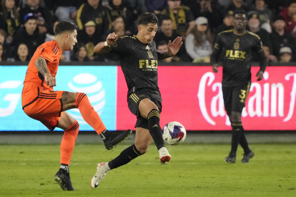 Los Angeles FC forward Cristian Olivera, center, moves the ball past Houston Dynamo defender Franco Escobar, left, during the second half in the MLS playoff Western Conference final soccer match Saturday, Dec. 2, 2023, in Los Angeles. (AP Photo/Marcio Jose Sanchez)