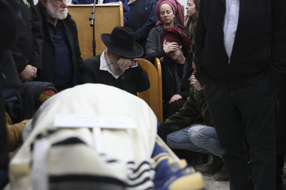Mourners gather around the body of Yehuda Dimentman, 25, during his funeral in Givat Shaul cemetery in Jerusalem, Friday, Dec. 17, 2021. Palestinian gunman opened fire Thursday night at a car filled with Jewish seminary students next to a West Bank settlement outpost, killing Yehuda Dimentman and lightly wounding two other people, Israeli officials said. (AP Photo/Oren Ziv)