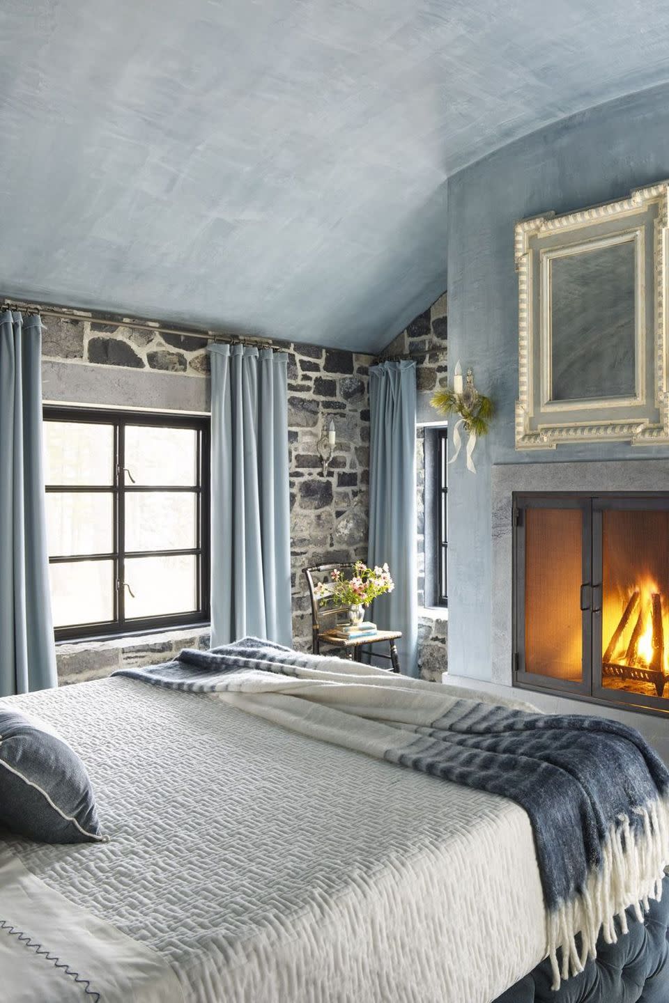 <p>Designed by Cathy Chapman, this bedroom is beautiful blend of snug, welcoming coziness and openness, partly thanks to the barrel ceiling. The custom blue-pigment plaster statement wall and ceiling complement the natural stones, which are from a nearby quarry. </p>