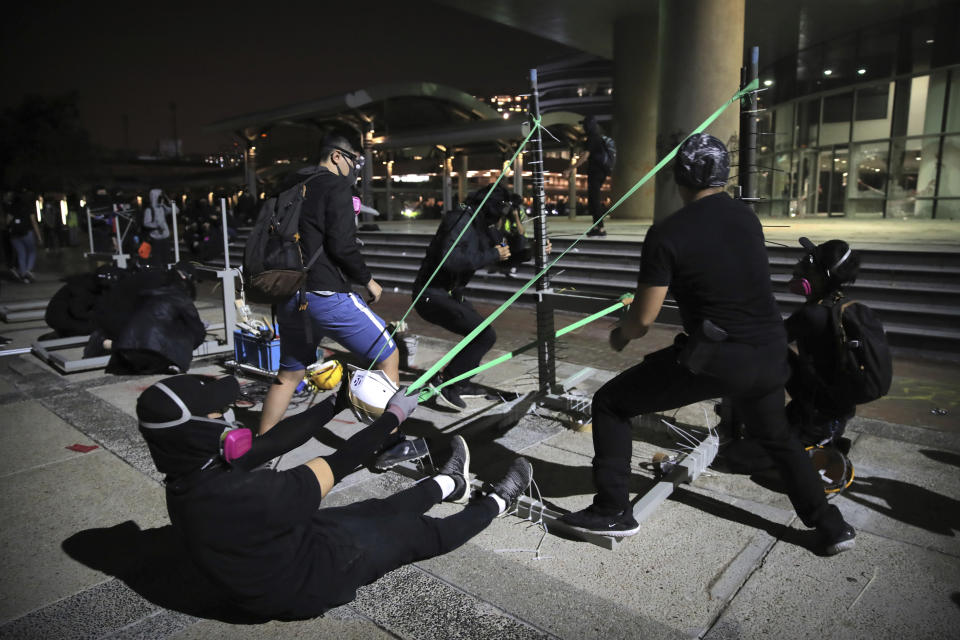 Protestors practice using a homemade slingshot at Hong Kong Polytechnic University in Hong Kong, Thursday, Nov. 14, 2019. Hong Kong police warned protesters on Thursday that they were moving "one step closer to terrorism" by sinking the city into chaos, as riot squads skirmished with militant students at major universities. (AP Photo/Kin Cheung)