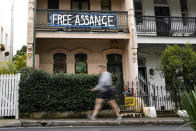 FILE - A pedestrian walks past a house with a sign in support of WikiLeaks founder Julian Assange in Sydney, Australia, on June 20, 2022. Australia's Prime Minister Anthony Albanese said, Wednesday, Nov. 30, 2022, that he had recently told U.S. President Joe Biden's administration to bring Wikileaks founder and Australian citizen Julian Assange's prosecution to a close.(AP Photo/Mark Baker, File)