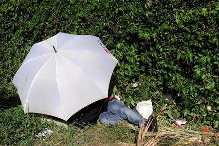A migrant sleeps under an umbrella as he waits at the main bus station in Istanbul, Turkey, September 15, 2015. REUTERS/Yagiz Karahan