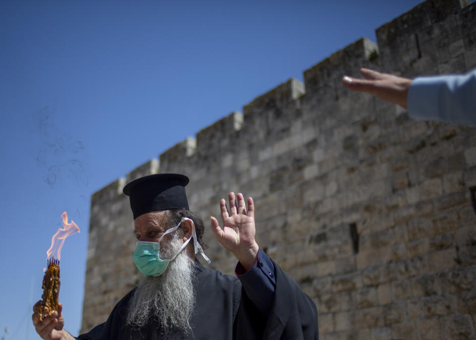 An Orthodox clergyman holds holy fire to transfer to predominantly Orthodox countries from the Church of the Holy Sepulchre, traditionally believed by many Christians to be the site of the crucifixion and burial of Jesus Christ, in Jerusalem's old city the traditional Holy Fire ceremony was called off amid coronavirus, Saturday, April 18, 2020. A few clergymen on Saturday marked the Holy Fire ceremony as the coronavirus pandemic prevented thousands of Orthodox Christians from participating in one of their most ancient and mysterious rituals at the Jerusalem church marking the site of Jesus' tomb.(AP Photo/Ariel Schalit)