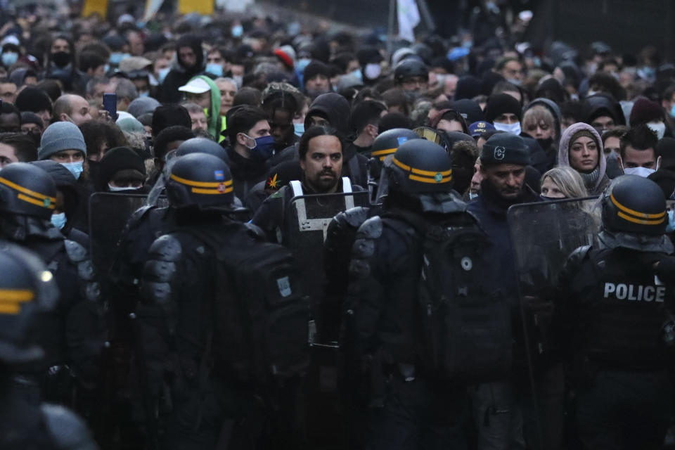 Protesters face riot police officers during a protest against a proposed security bill, Saturday, Dec.12, 2020 in Paris. The bill's most contested measure could make it more difficult for people to film police officers. It aims to outlaw the publication of images with intent to cause harm to police. The provision has caused such an uproar that the government has decided to rewrite it. Critics fear the law could erode press freedom and make it more difficult to expose police brutality. (AP Photo/Thibault Camus)