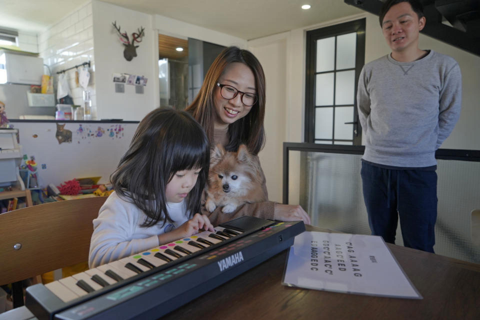 Mike Hui, right, looks at her daughter practicing piano at home in Hong Kong on Jan. 31, 2021. Until early April, Hui was a photojournalist for the Apple Daily, a pro-democracy newspaper that shut down following the arrest of five top editors and executives and the freezing of its assets under a national security law that China's ruling Communist Party imposed on Hong Kong as part of the crackdown. (AP Photo/Kin Cheung)