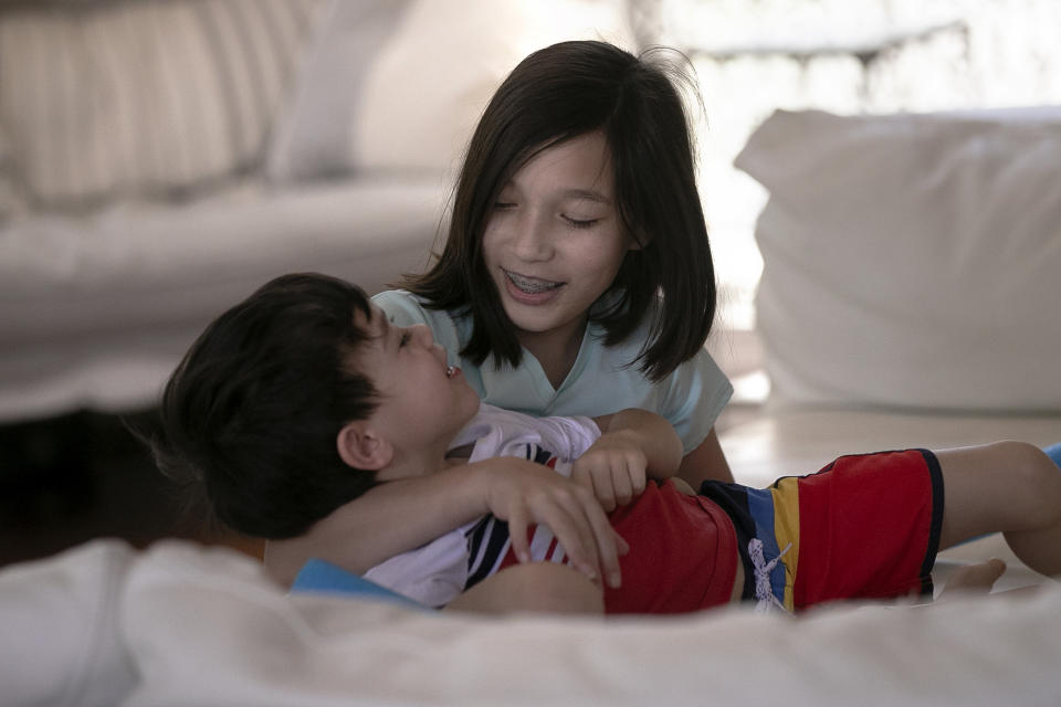 Juliet Daly, 12, plays with her brother Dominic, 5, in their family home in Covington, La., Thursday, April 30, 2020. A team of pediatric cardiology specialists found that Juliet had acute fulminant myocarditis (AFM), an uncommon heart condition that tends to present with sudden onset acute heart failure, cardiogenic shock or life-threatening arrhythmias. A nasal swab confirmed that Juliet was also COVID-19 positive and that she had a second viral infection – adenovirus. (AP Photo/Gerald Herbert)