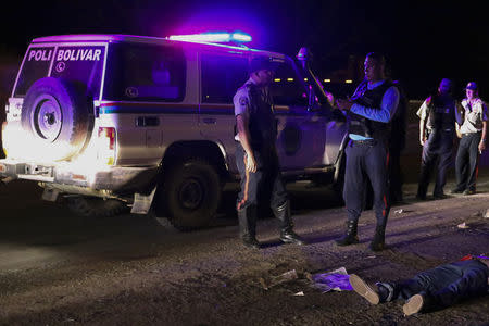 Police officers stand near the body of Anzoategui state policeman Mario Figueroa after he was shot dead in Barcelona, in the state of Anzoategui January 24, 2015. REUTERS/Stringer