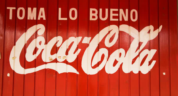 MEXICO Todos Santos Advertising for Coca Cola in Spanish painted on side of red wooden building Toma lo Bueno slogan