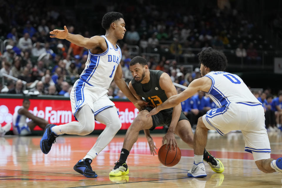 Miami guard Jakai Robinson (13) drives to the basket against Duke guards Caleb Foster (1) and Jared McCain (0) during the second half of an NCAA college basketball game, Wednesday, Feb. 21, 2024, in Coral Gables, Fla. (AP Photo/Wilfredo Lee)