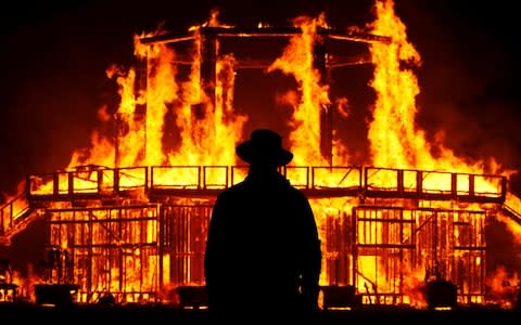 A Burning Man Ranger guards the inner perimeter around the effigy of "The Man" as it burns at the culmination of the annual Burning Man arts and music festival in the Black Rock desert of Nevada - Credit: Reuters