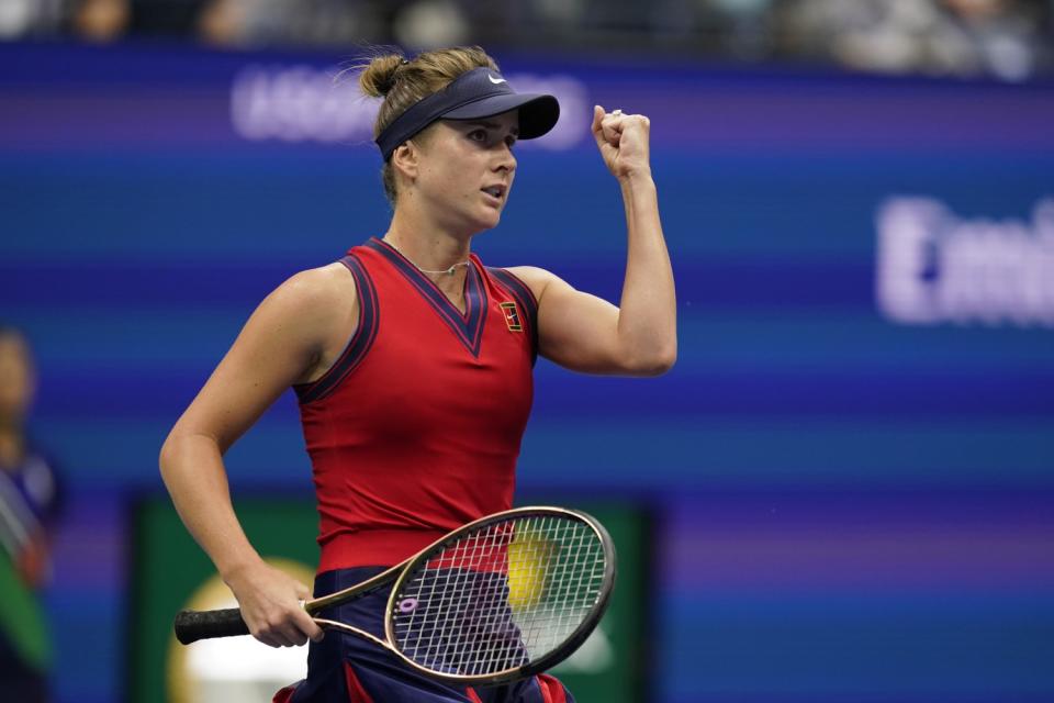 Elina Svitolina, holding a racket, punches a fist into the air.